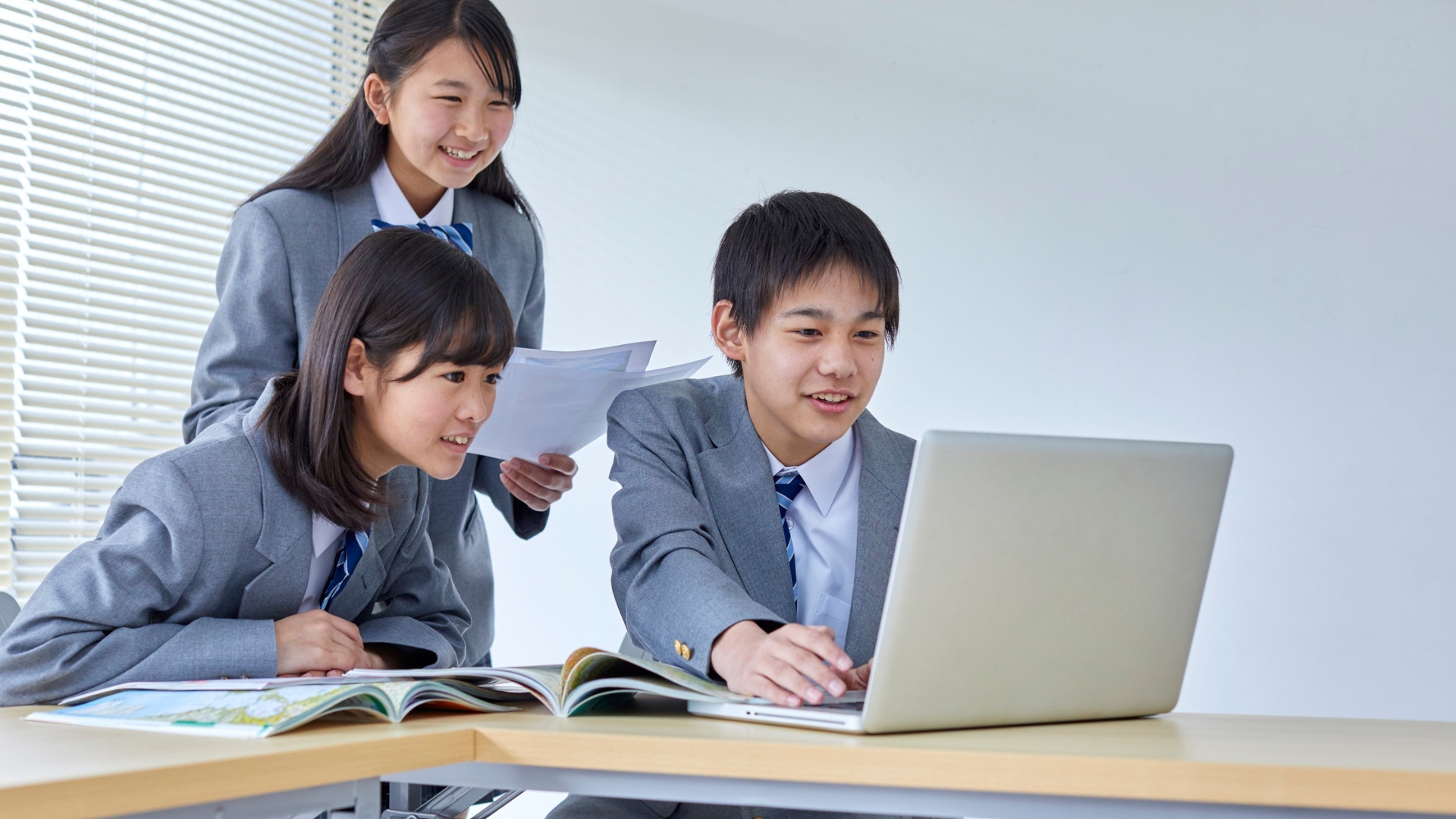 ノートパソコンで共同学習する生徒たち